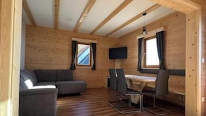 A wooden cabin interior with a sofa, dining table, and chairs. - Apartment Smreka - Amazing place in the mountains - Pr Ambružarju (Kranj)