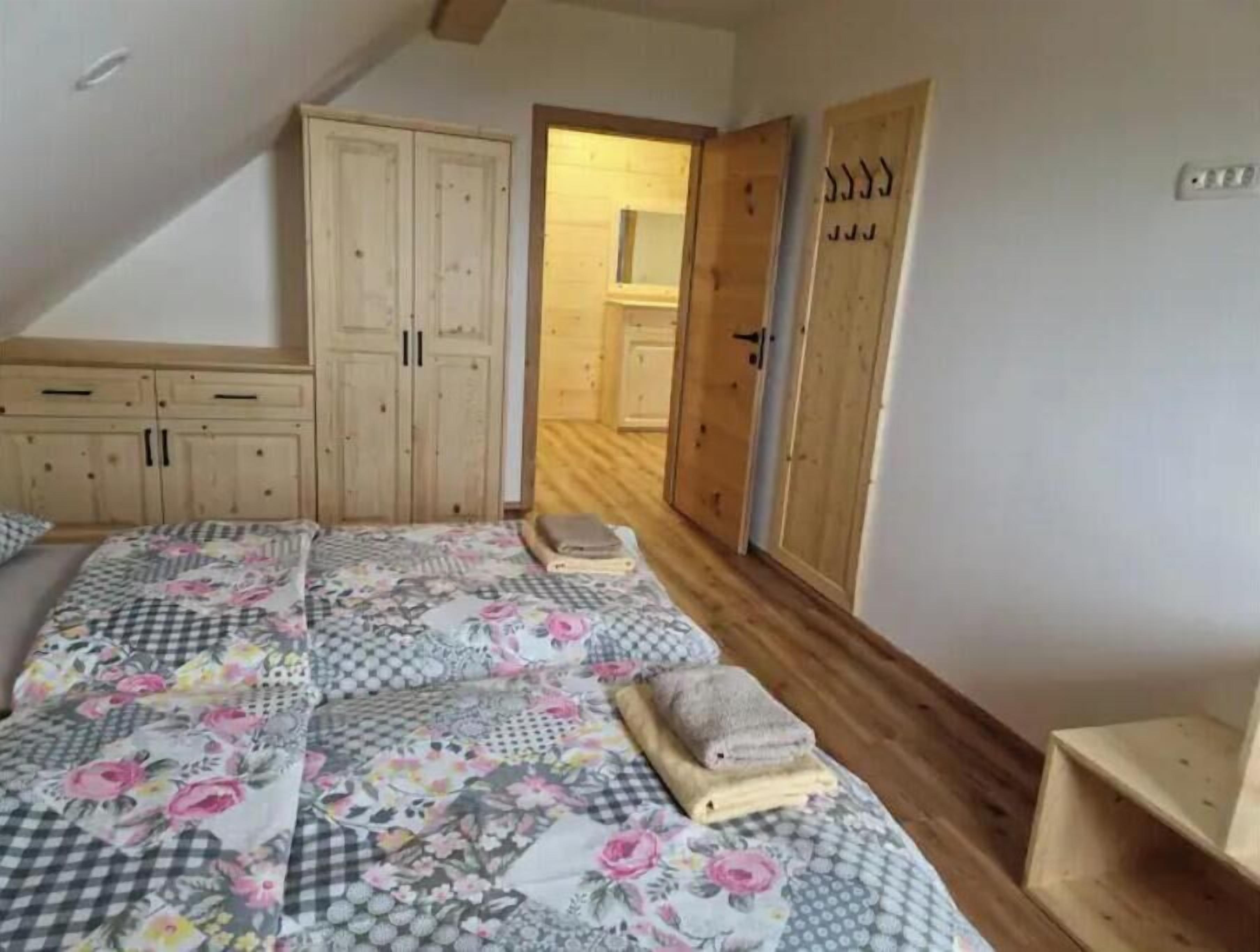 Ein Schlafzimmer mit einem Bett, einem Holzschrank und einer Tür zu einem weiteren Raum.