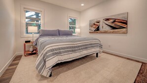 A bedroom with a bed, two bedside tables, a ceiling fan, and a painting on the wall.