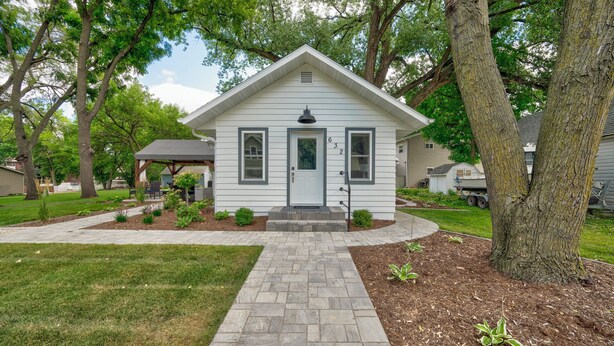 A small, single-story house with a front porch, a driveway, and a well-maintained lawn.