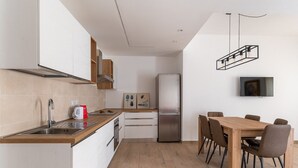 A modern kitchen with a stainless steel refrigerator, wooden cabinets, and a dining area with a wooden table and chairs. - Russu Suli Apartment 1 by Wonderful Italy (Siracusa)