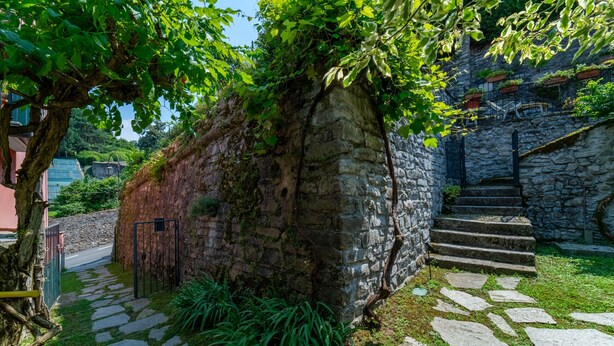 Un muro de piedra con una escalera que sube a un edificio.