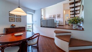 Un comedor con una mesa redonda y sillas, una escalera y un florero.