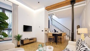 A modern living room with a sofa, coffee table, and a TV. There's a staircase leading to an upper floor. - Genteel Home Lagar II (Seville)