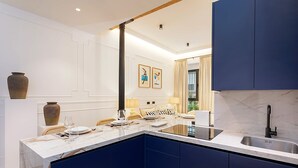 A modern kitchen with dark blue cabinets, a white marble countertop, and a built-in sink. - Genteel Home Lagar II (Seville)
