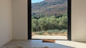 Una habitación con un amplio ventanal corredero que da a una vista de la colina. Hay dos toallas enrolladas en el suelo.