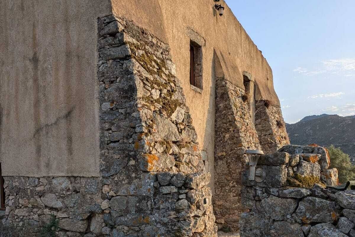 A stone building with a rough, textured exterior and a small window.