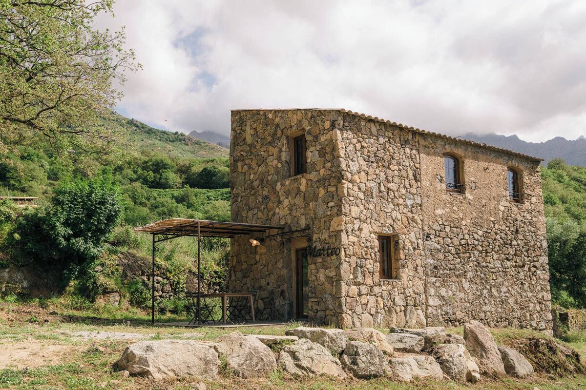 A stone building with a small porch and a wooden table.