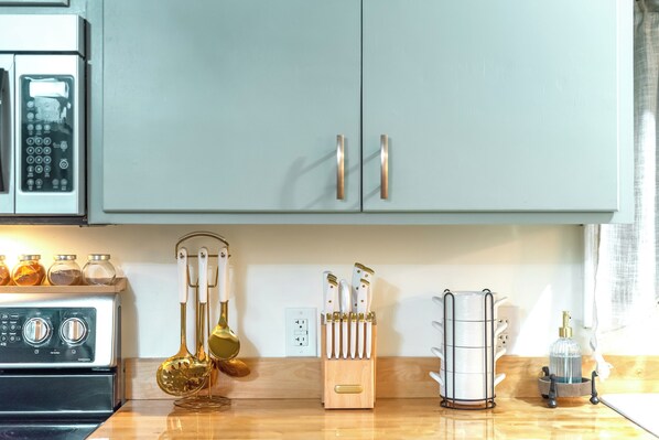 A kitchen with a stove, a knife block, a spice rack, and a coffee machine.