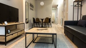 A modern living room with a flat-screen TV, a coffee table, a sofa, and a dining area with chairs. - New Apartment Boston - Center/Comfort/Wi-Fi (Valladolid)