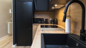 A compact kitchen with a black refrigerator, a coffee maker, a kettle, and a sink with a black faucet. - New Apartment Boston - Center/Comfort/Wi-Fi (Valladolid)