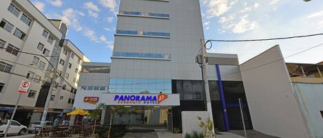 Un edificio moderno con un letrero que dice "Panorama Economic Hotel" y la entrada a un "Garage".