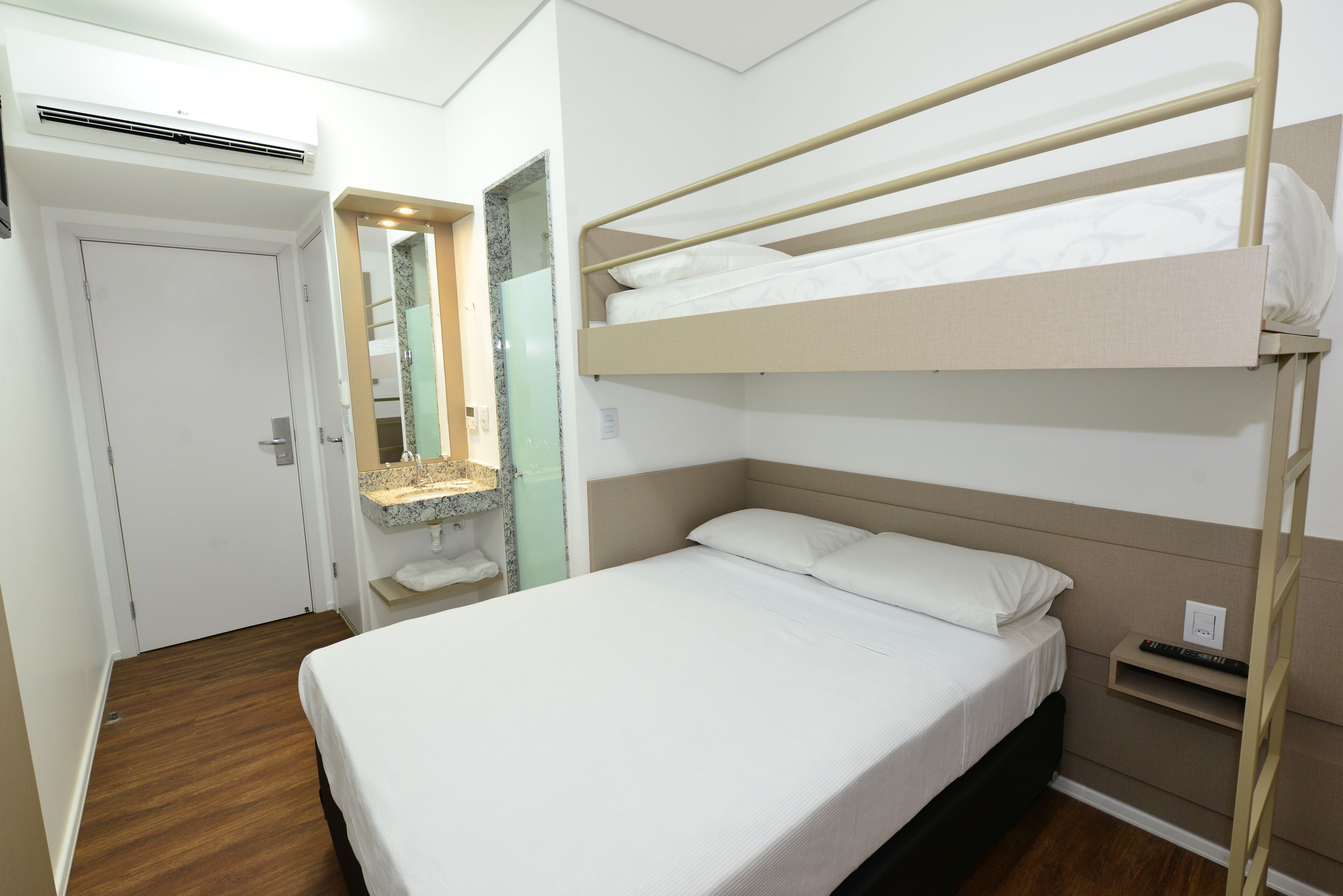A bunk bed with a headboard, a small bedside table, and a mirror above the sink.