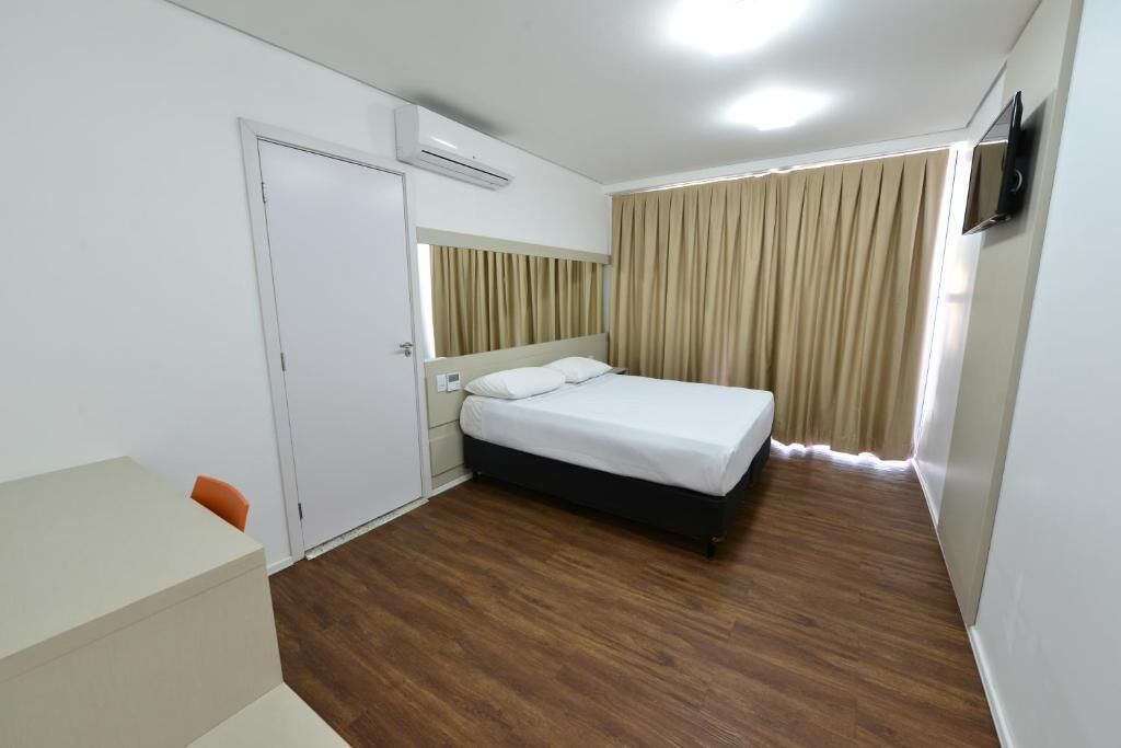 A hotel room with a bed, a desk, and a TV.