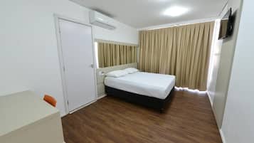 Una habitación de hotel con una cama, un escritorio y un televisor.