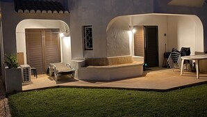 A courtyard with a seating area, a table, and chairs. There are two doors and a window with a decorative grille. - Casa Sophie Albufeira Apartment With 2 Bedrooms (Albufeira)