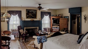 Quarto com lareira, cama, escrivaninha e poltrona.