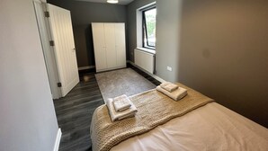 Une chambre à coucher avec un lit, une fenêtre, une armoire et un luminaire au plafond.
