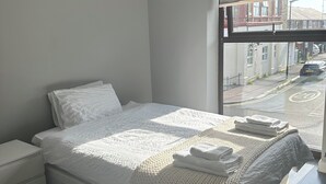 Une chambre avec un grand lit, une table de chevet et une fenêtre donnant sur la rue.