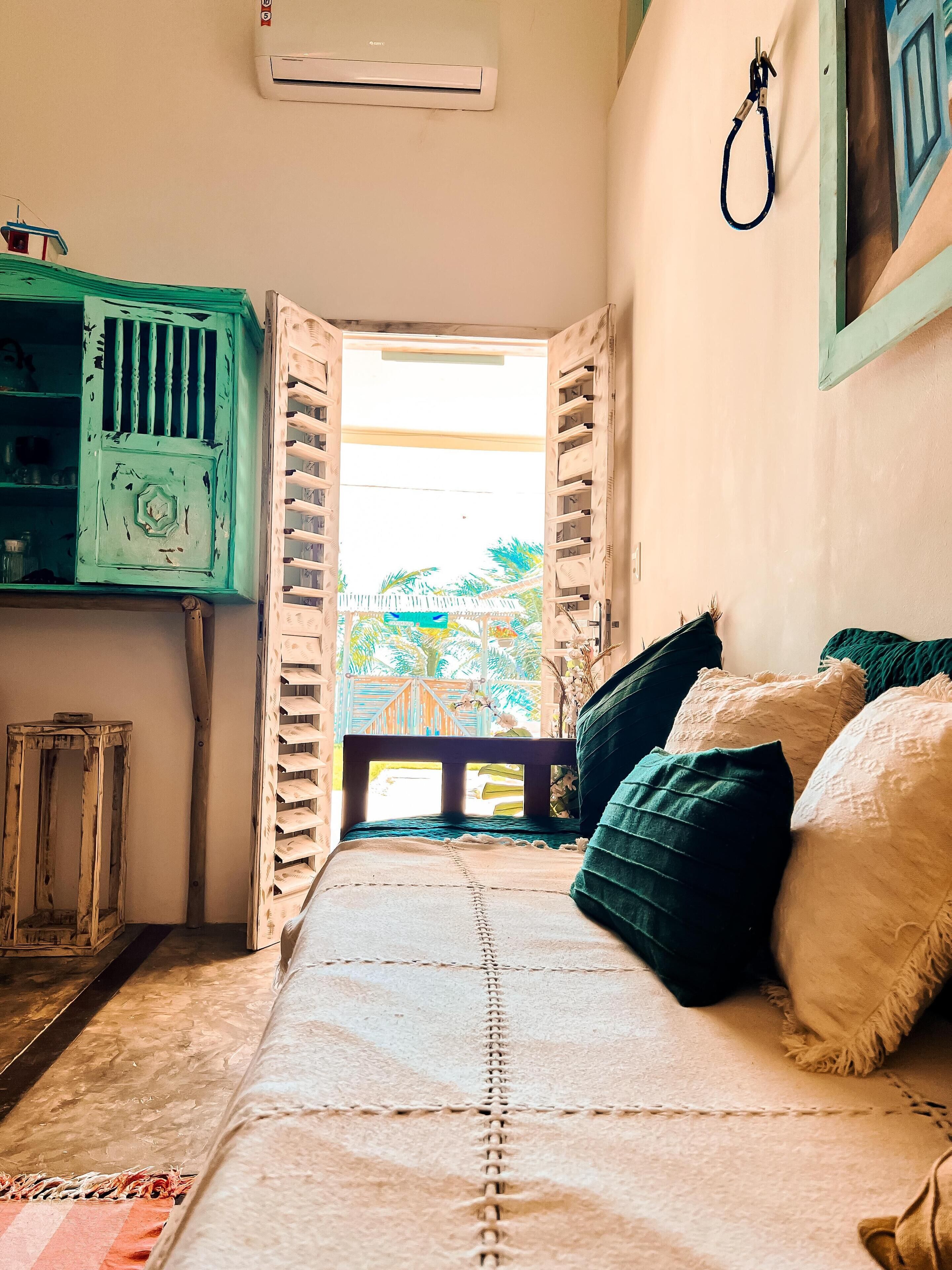 Un dormitorio con cama, un armario de madera, una mesita y una ventana con cortinas.