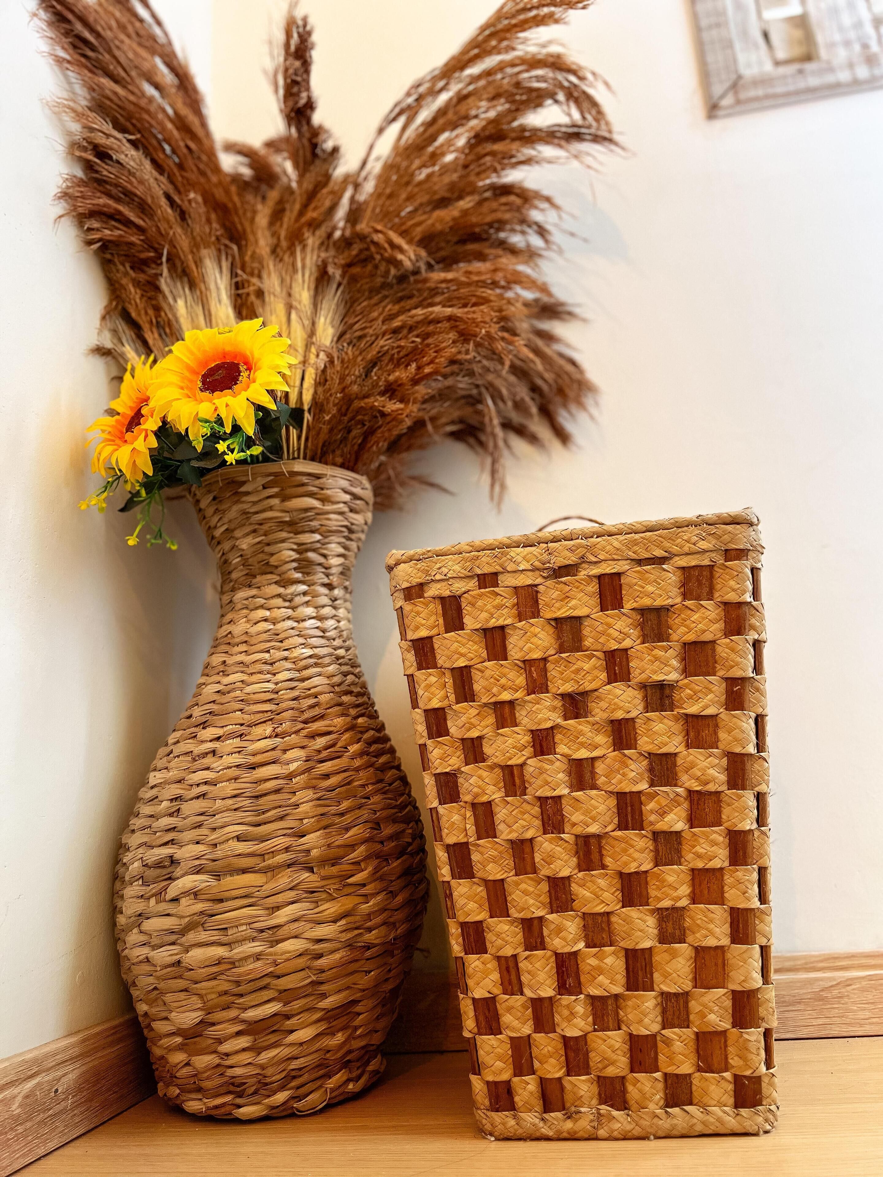 A woven basket and a vase with dried plants and yellow flowers.