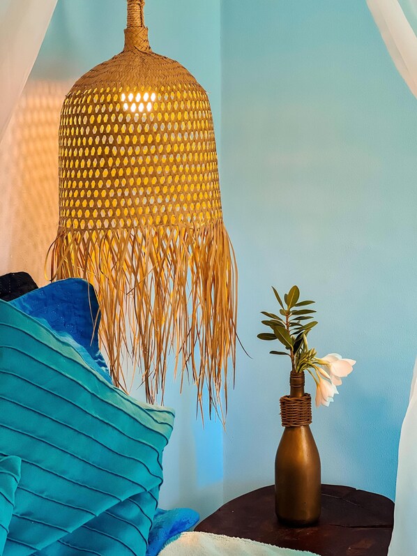 A room with a hanging lamp, a vase with flowers, and a blue fabric. - Asas del Mar (Aracati)