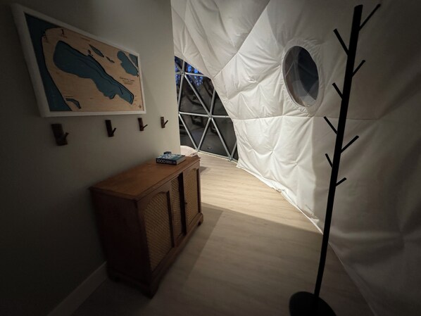 Uma estrutura em forma de tenda com uma janela circular, um armário de madeira e um mapa na parede.