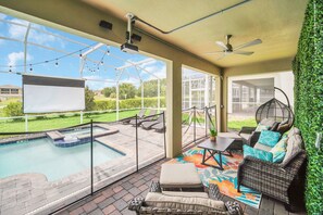 A covered outdoor area with a pool, seating, and a projector screen. - Marvel Game Room • Poolside Theater • Private Pool & Spa • Near Disney • Resort (Davenport)