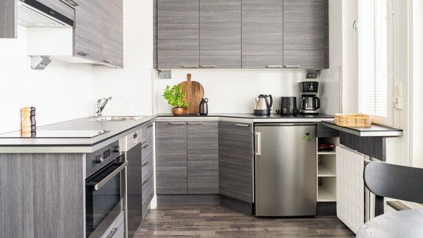 A modern kitchen with grey cabinetry, a built-in oven, and a compact refrigerator. - CentralStudio with Rooftop Terrace (Helsinki)