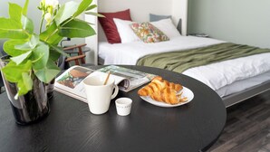 A neatly arranged breakfast table with a plant, a coffee cup, a small cup, and a plate of croissants. - CentralStudio with Rooftop Terrace (Helsinki)