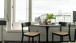 A room with a round table and two chairs, a potted plant, and a window with blinds. - CentralStudio with Rooftop Terrace (Helsinki)