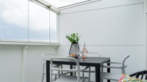 A balcony with a table and chairs, a potted plant, and a bottle. - CentralStudio with Rooftop Terrace (Helsinki)