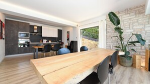 A modern kitchen with dark cabinets, a wooden dining table, and black chairs. - VILLA MIMOSA - Stunning lake view, private garden, swimming pool and Jacuzzi (Brenzone sul Garda)