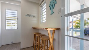 Ein Zimmer mit einer Holzhocker-Anordnung, einem Fenster mit Jalousien und einer an der Wand befestigten Fischdekoration.