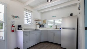 Eine Küche mit weißen Schränken, einem Kühlschrank, einer Mikrowelle und einer Kaffeemaschine.