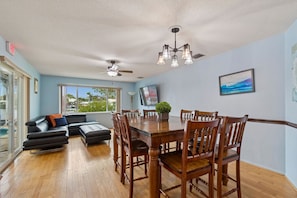 A dining area with a wooden table and chairs, a ceiling fan, and a large window.
