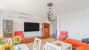 Una sala moderna con televisor de pantalla plana, muebles de madera y un sofá naranja brillante.