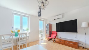 Una sala moderna con comedor, televisor y una silla roja.