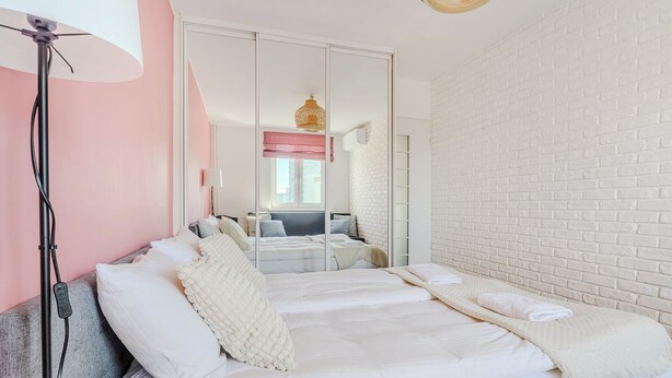 Un dormitorio con cama, armario, espejo y lámpara.
