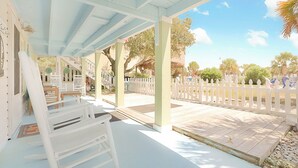 Un espace extérieur abrité, doté de bancs blancs, d’une terrasse en bois et d’une clôture blanche à lattes.