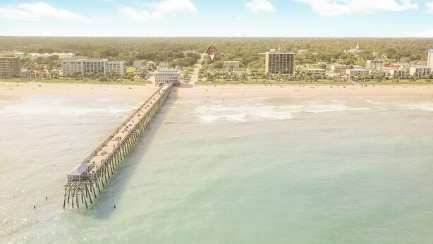 Une jetée qui s’avance sur une plage, avec des bâtiments en arrière-plan.