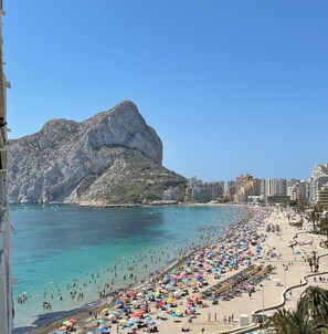 A crowded beach with numerous umbrellas and people enjoying the sun.
