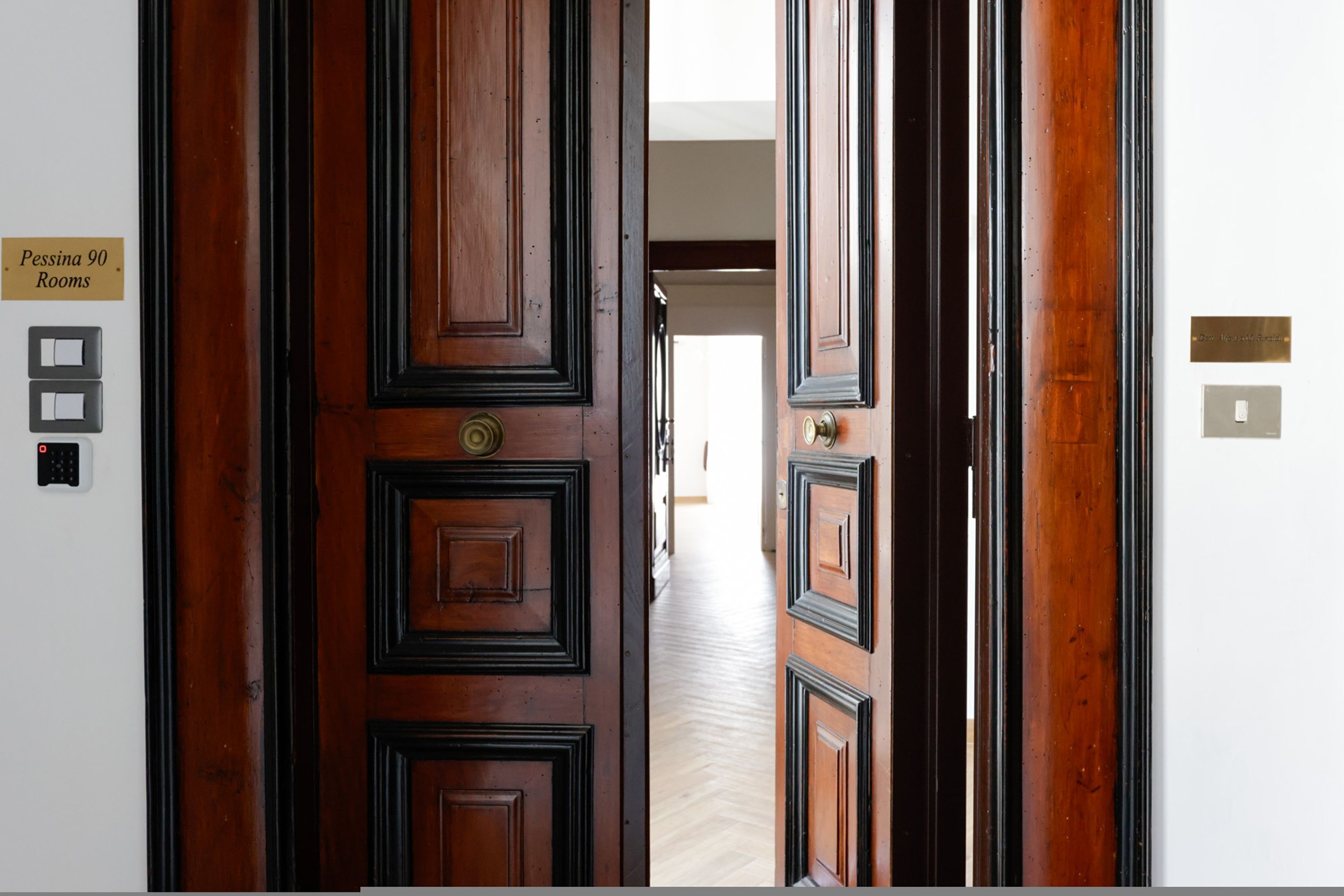 Une porte en bois avec une enseigne indiquant « Pessina, 90 chambres ».