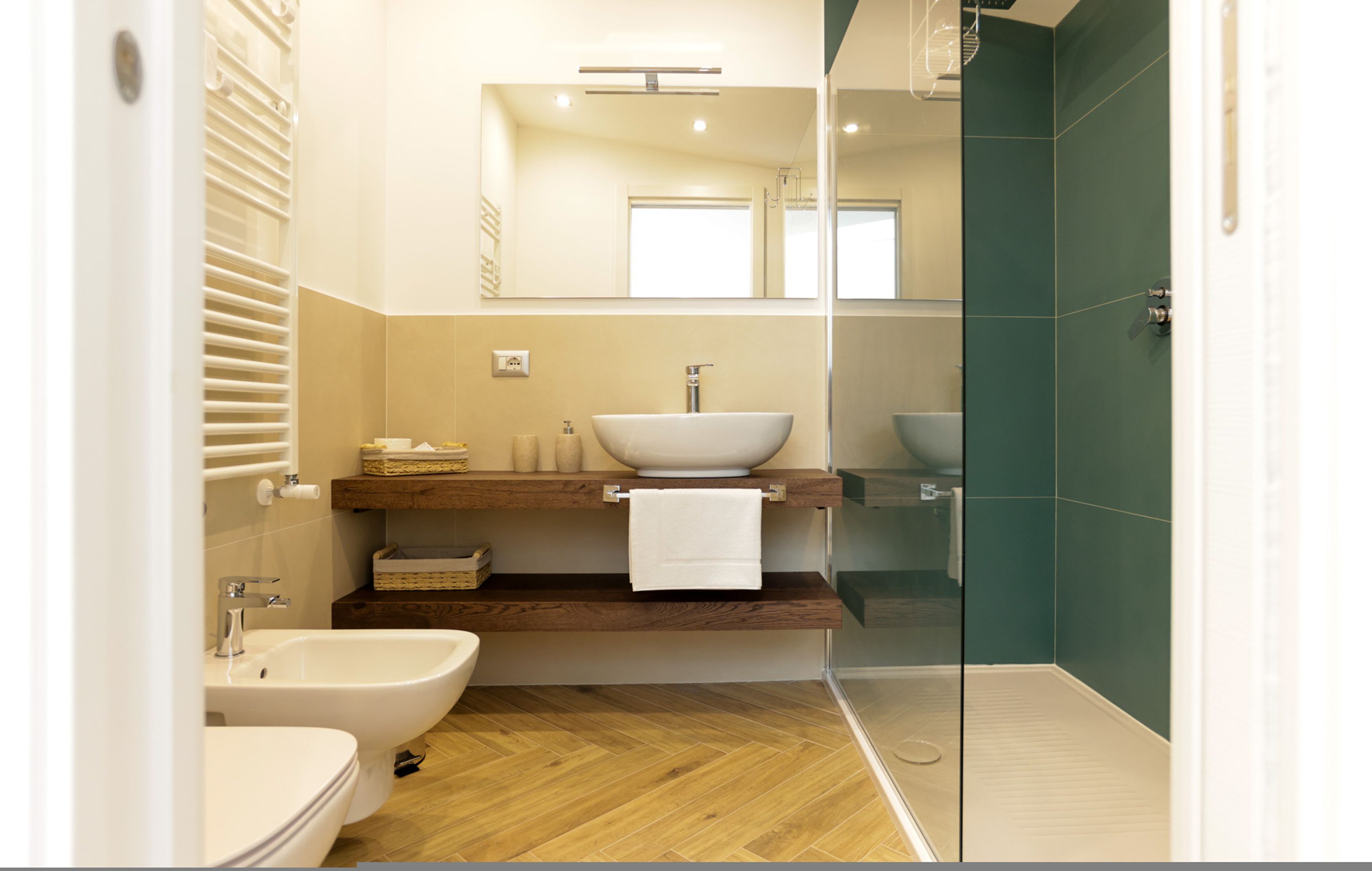 A modern bathroom with a bidet, a large sink, a mirror, and a shower area.