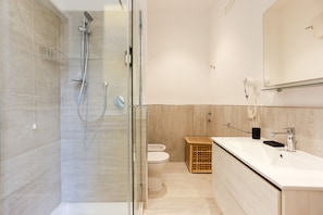 A modern bathroom with a glass-enclosed shower, a toilet, and a sink with a mirror above. - Il Centrale - Camera 1 (Naples)
