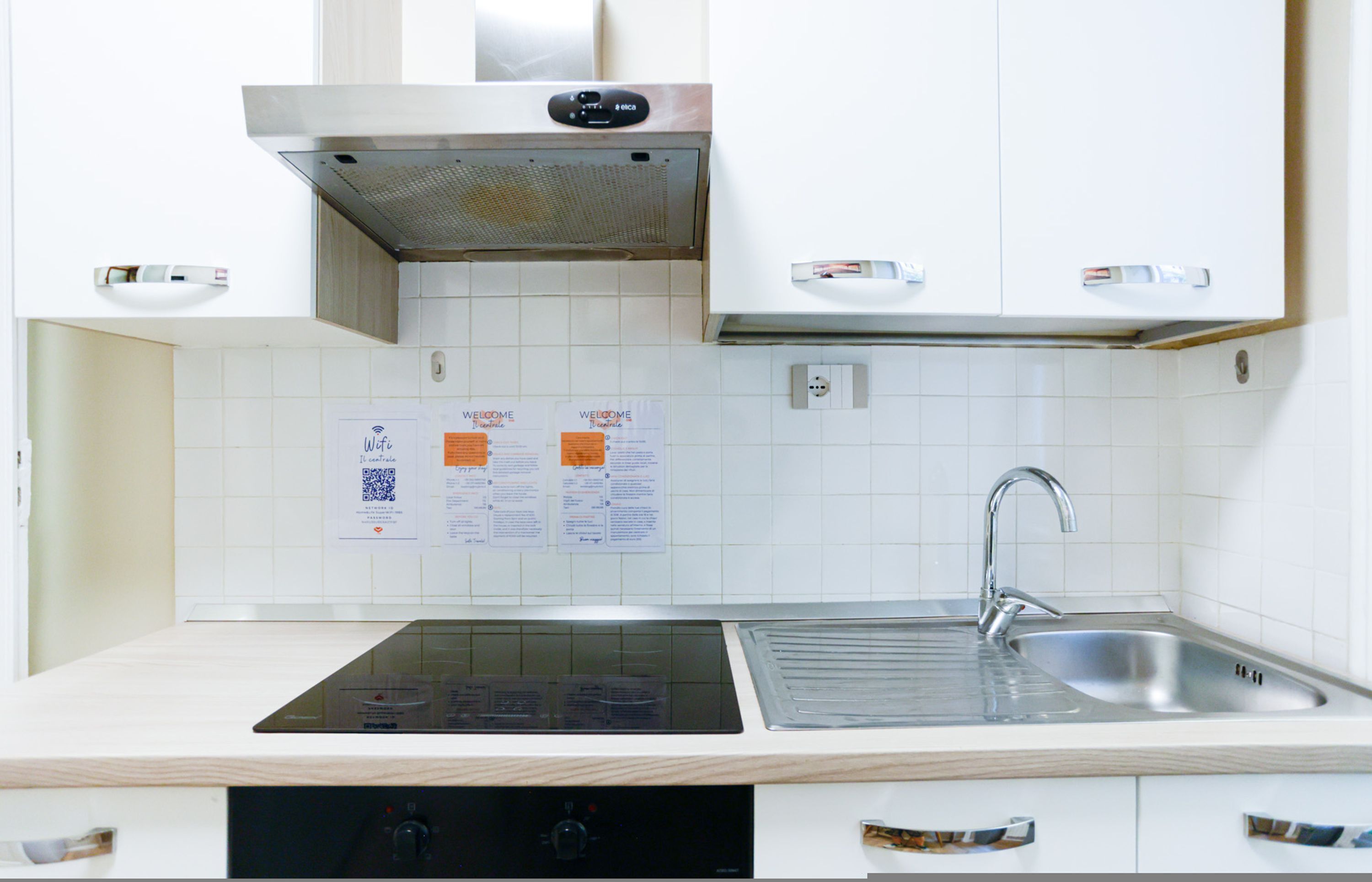 Une cuisine moderne avec des meubles blancs, un évier en acier inoxydable et une plaque de cuisson à induction.