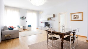A modern living room with a dining table, chairs, a sofa, and a TV. - Riviera di Chiaia 207 (Naples)