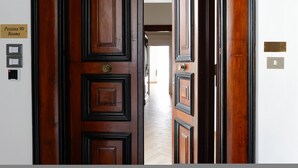 A wooden door with a sign reading "Pessina 90 Rooms" and a hallway leading to a bright room. - Pessina 90 Rooms - Camera 1 (Naples)