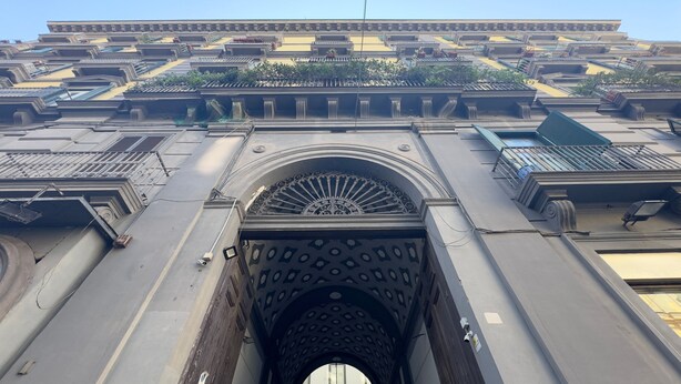 A building facade with a central arched entrance, multiple balconies, and decorative elements. - Pessina 90 Rooms - Camera 1 (Naples)