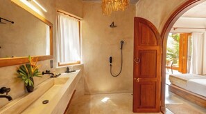 Bathroom features a modern vanity, shower with handheld showerhead, and a potted plant.